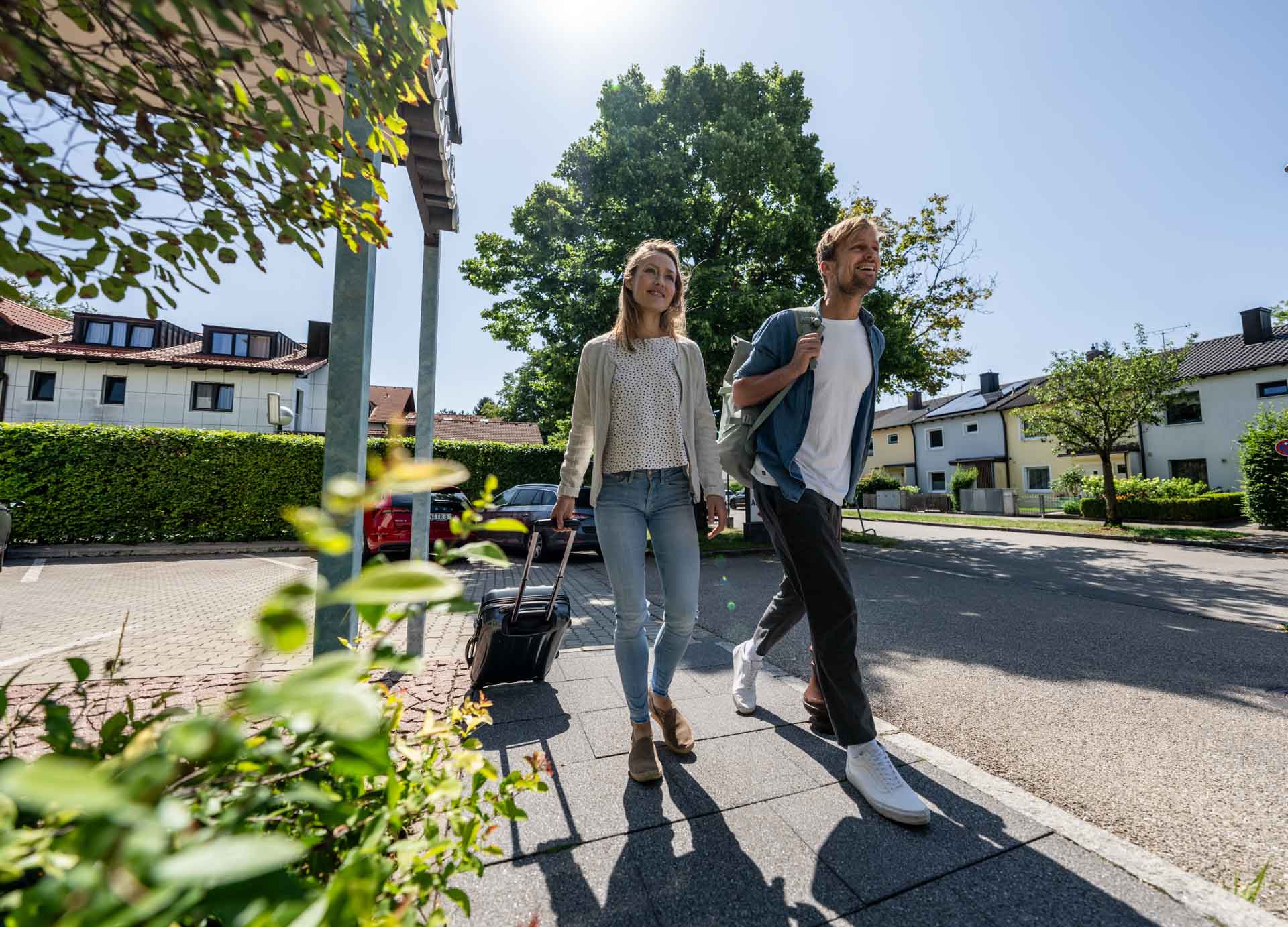 Mann und Frau, welche mit Trollie und Rucksack auf dem Weg in das Hotel sind.