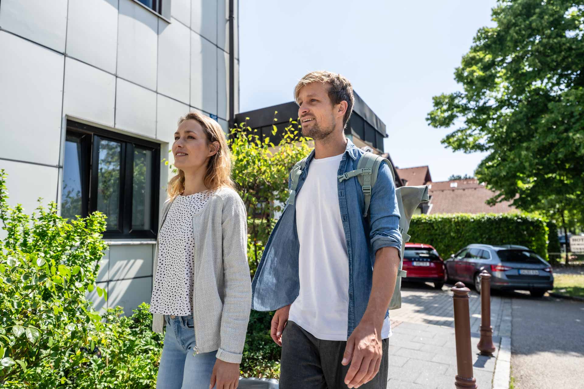 Mann und Frau, welche mit Trollie und Rucksack auf dem Weg zu einer Freizeitbeschäftigung.